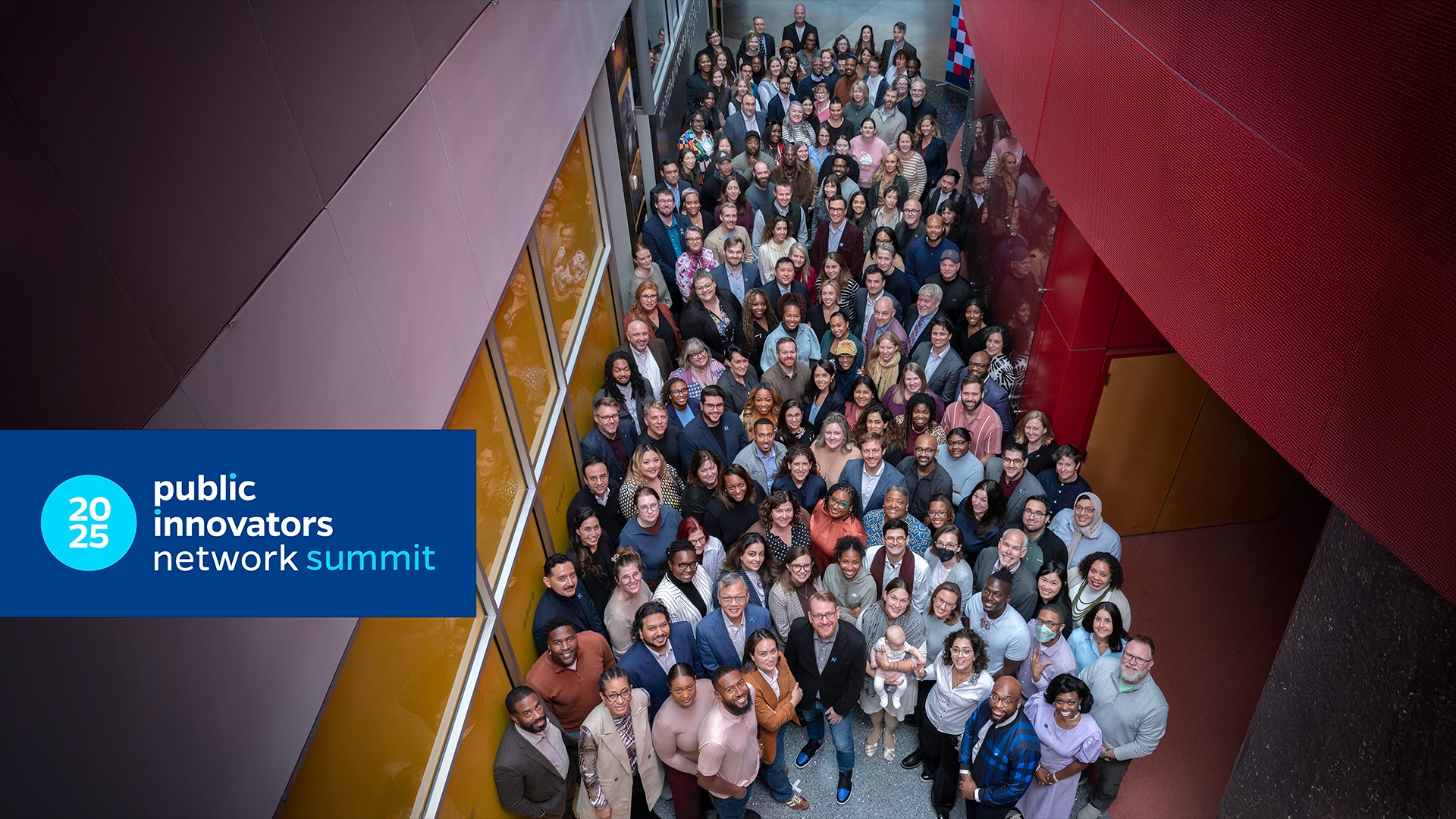 Group of attendees at the 2025 Public Innovators Network Summit, posing in a building's atrium.