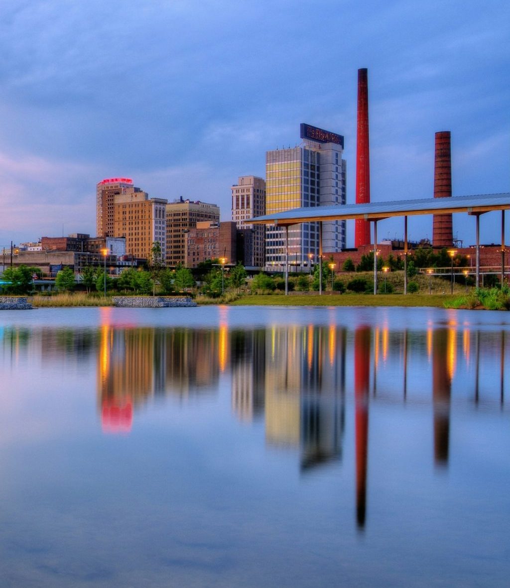 Birmingham, Alabama View of downtown Birmingham, Alabama skyline at dusk with reflections visible in the water below.