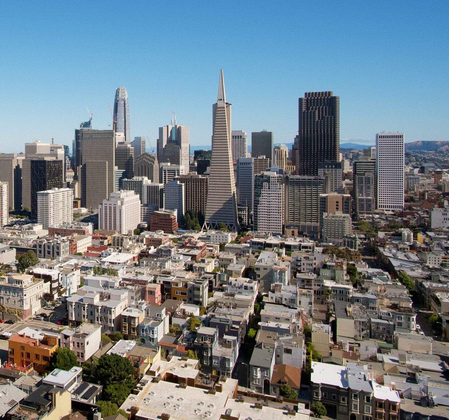 San Francisco, California Aerial view of downtown San Francisco featuring the Transamerica Pyramid and Salesforce Tower amidst other buildings under clear blue skies.